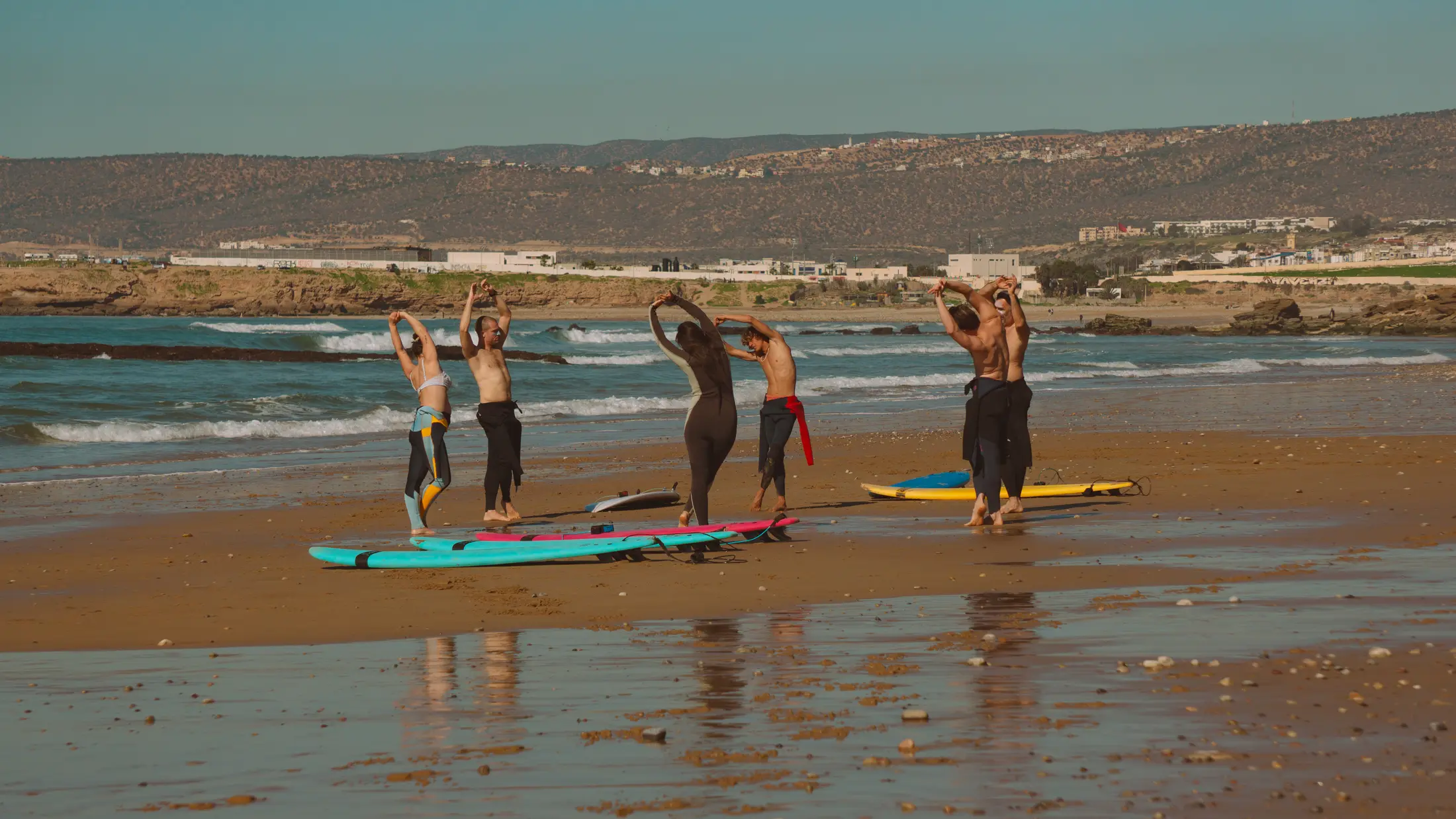 Surf group stretching together on the beach