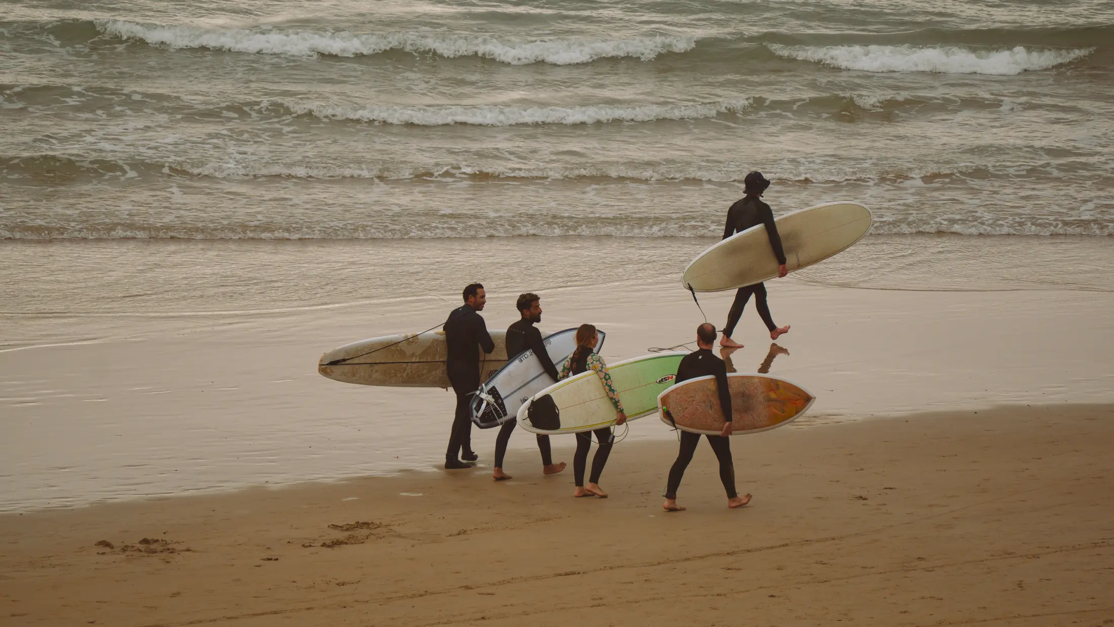 A group of surfers walking into the ocean together