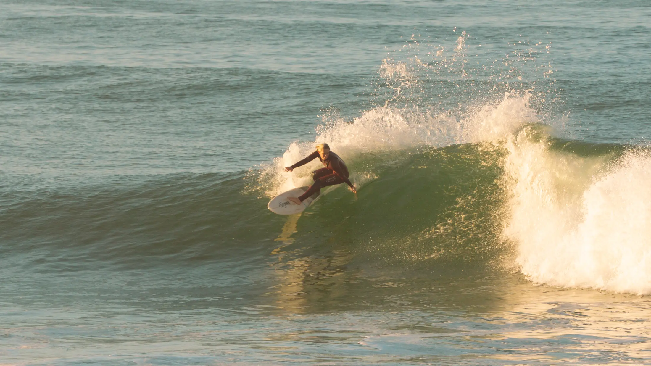 Surfer carving on a green wave in golden light